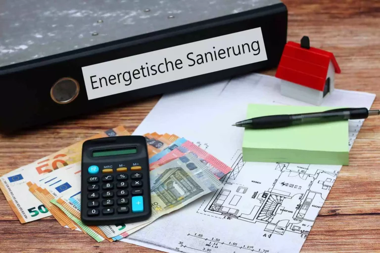 Aktenordner mit der Aufschrift Energetische Sanierung, daneben Grundriss, Taschenrechner und Geldscheine