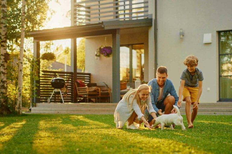 Glückliche Familie spielt im Garten nach der erfolgreichen Finanzierung des 1. Hauskaufs