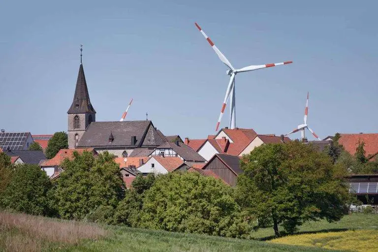 Große Windräder ragen über Dächer einer Gemeinde hinaus